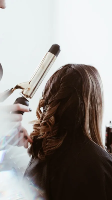 Stylist curling a client's hair for a bridal style
